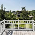 Deck with white railing and view of green landscape and houses.