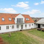 White house with red tiled roof and balcony. Lawn and outbuilding.