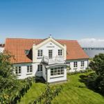 White house with red roof, balcony, and view of water