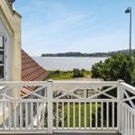 Terrace with white railing offers view of water and greenery.