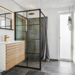 Bathroom with shower enclosure, sink, and mirror.