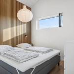 Bedroom with bed, wooden wall, window, and lamps.