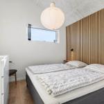 Bedroom with bed, wooden wall, and window.