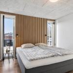 Bedroom with double bed, wooden wall, and balcony door.