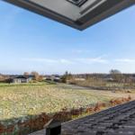 Wide view of green field and holiday homes under clear sky.