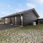 Modern wooden house with garden and soccer goal. Snow covers the lawn.