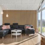 A living room with gray sofa, wooden wall, and large window.