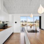 Modern kitchen with wooden countertop and large window view.