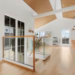 Haus mit Holzboden, Glasgeländer und Küchenbereich im Hintergrund.