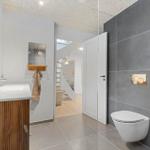 Badezimmer mit Waschbecken, Toilette und Dusche. Durchgang zur Treppe.