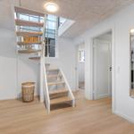 Haus mit Treppe, Spiegel und Eingangsbereich mit hellen Wänden und Holzboden.