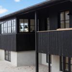 Moderne Ferienwohnung mit schwarzem Holzverkleidung und großzügigen Fenstern.