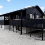 Schwarzes Haus mit Balkon auf Sandstrand, umgeben von Bäumen.
