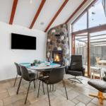 Essbereich mit Esstisch, Stühlen und Kamin. Große Glasfront mit Sitzgelegenheiten.