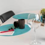 Tisch mit Platzdeckchen, Gläsern, Tasse, Würfeln und Stift