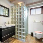 Badezimmer mit Glasblockwand, Waschbecken und Toilette.