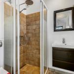 Dusche mit Glaswand, Waschbecken und Spiegel im Badezimmer