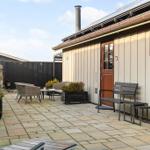 Terrasse mit Sitzgelegenheiten und Pflanzen vor einem Holzhaus.