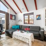 Wohnzimmer mit Sofa, Couchtisch und Sitzgelegenheit. Holzbalken und Fenster sichtbar.