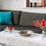 Grauer Sofa mit türkisen Kissen, Tisch mit Blumen und Schale.