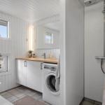 Bathroom with shower, washing machine, and sink with mirror.