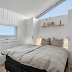 Bedroom with bed, window, and skylight. Wooden floor and white walls.