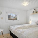 Bedroom with bed, window, and wall shelf. Wooden walls and floor.