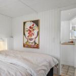 Bedroom with bed and wall art. Passage to living area with sea view.