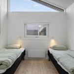Two beds, window and wooden floor in a bedroom.