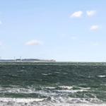 Sea view with wind turbines and rocky horizon through window