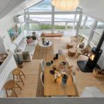 Living and dining area with fireplace and sea view through large windows.