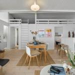 Living area with dining table, fireplace, and upper level. Modern furnishings with wooden floor.