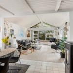 Living and dining area with wooden floor, large windows, and wood stove.