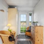 Hall with wooden furniture, wicker chairs, and view of grassland.