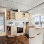 Kitchen with wooden cabinets, stove, and window with view.