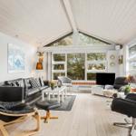 Living room with black leather furniture, wooden floor, and large windows.