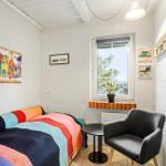 Room with bed, armchair, and window overlooking trees.