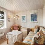 Living room with sofa, chair, and table. Wall art and window visible.