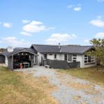 A house with gray roof and white facade. Courtyard with gravel path and wooden railings.