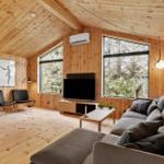 Living room with wooden walls, sofa, TV, and large windows.