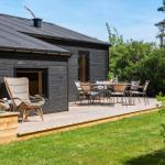 Black wooden house with terrace, garden furniture, and plants.