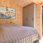 Bedroom with wooden walls, bed, and sliding door to terrace.