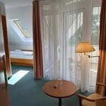 Zimmer mit Blick auf Balkon, Tisch, Stuhl und Bett im Hintergrund.