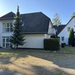Ein weißes Haus mit dunklem Dach und Garten. 