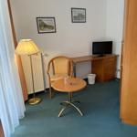 Zimmer mit Tisch, Stuhl, Schreibtisch und Fernseher.