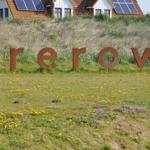 Large sign with the name Prerow on a green meadow with blooming flowers.