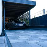 Schwarzer Mini Electric in geschützter Garage mit Pflastersteinbereich.