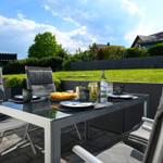 Terrasse mit Gartentisch, Stühlen und Essen im Freien.