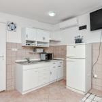 Küche mit weißen Schränken, Kühlschrank und TV an der Wand.