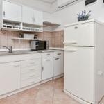 Küche mit weißen Schränken, Kühlschrank und Mikrowelle.